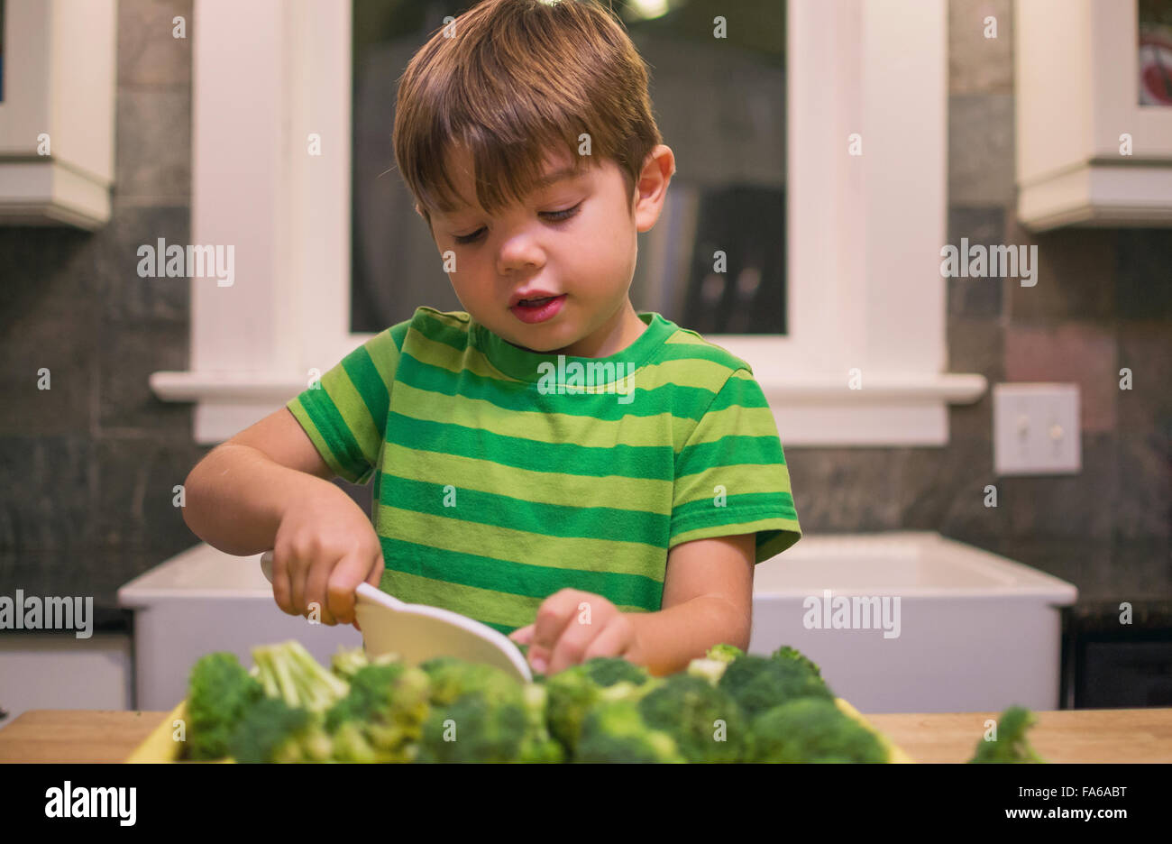Boy in kitchen chopping broccoli Stock Photo