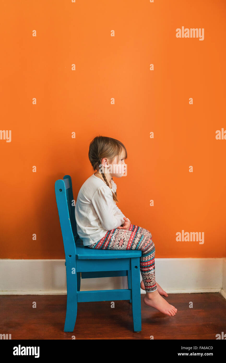 Girl sitting on a chair pouting Stock Photo