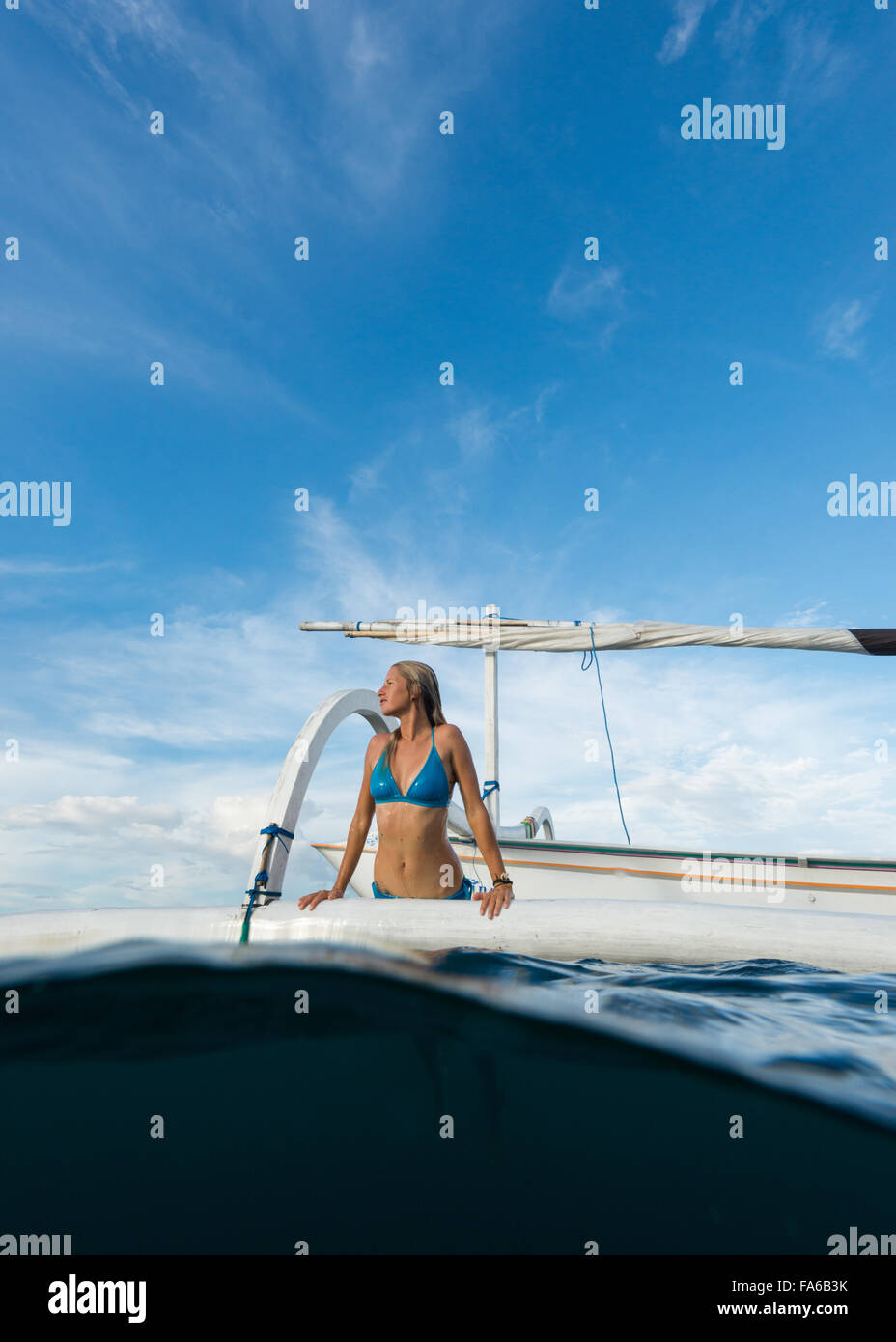 Woman getting out of the sea onto a boat, Bali, Indonesia Stock Photo