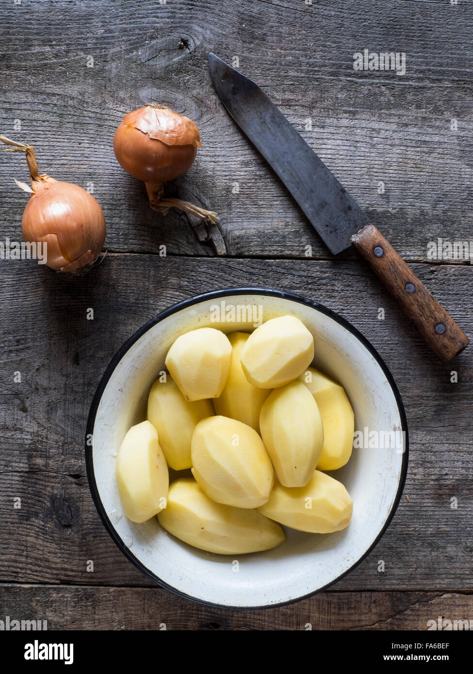Peeled potatoes, onions and knife on table Stock Photo