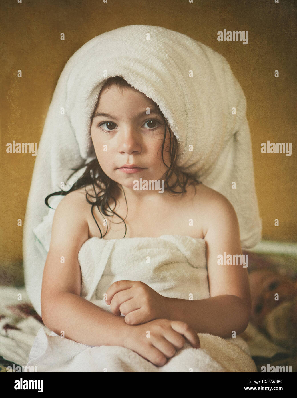 Portrait of a girl sitting on bed wrapped in towels after a bath Stock