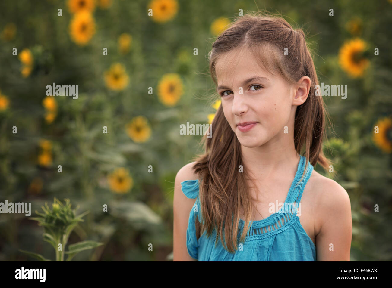 Girl standing in sunflower field smiling Stock Photo - Alamy
