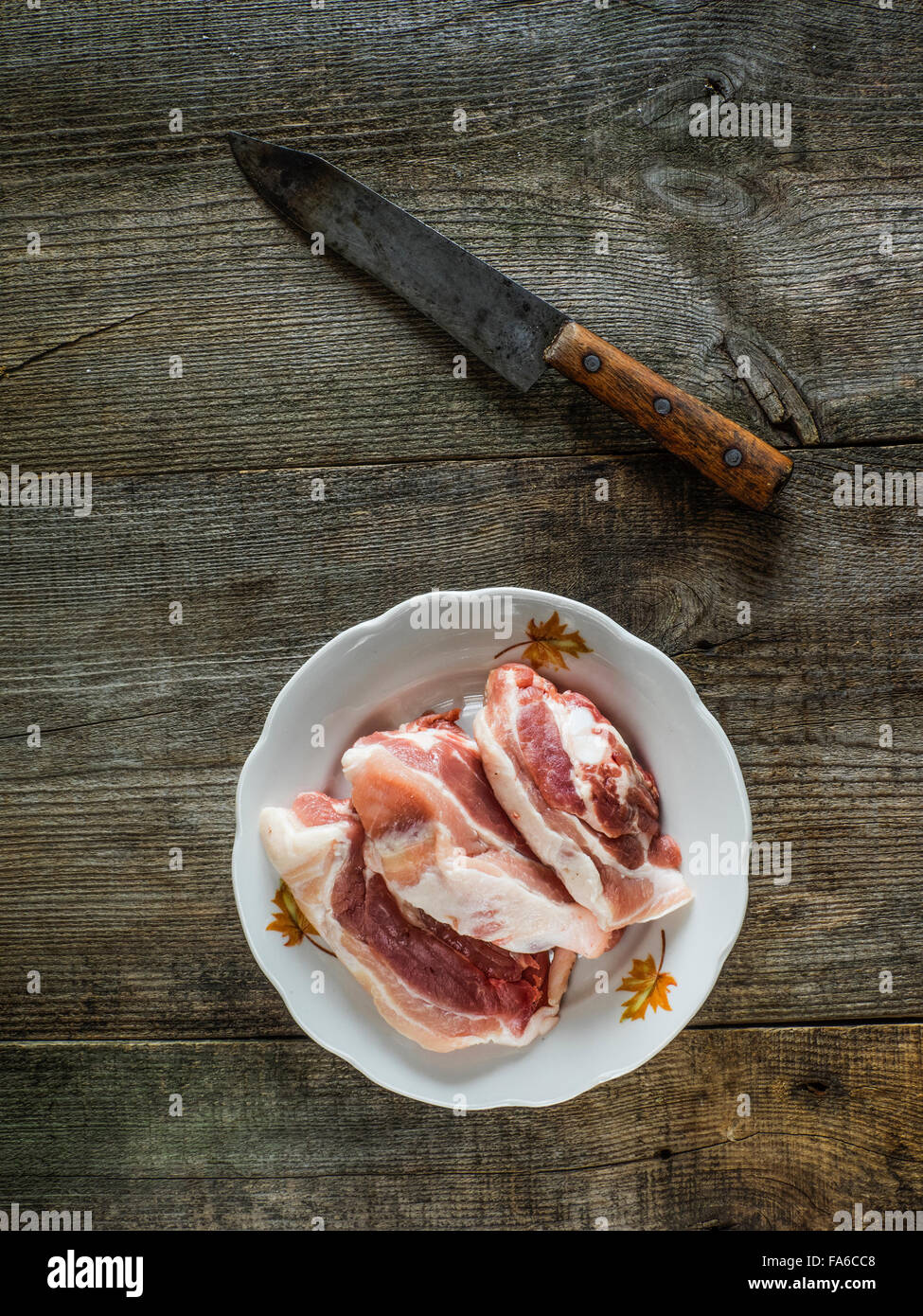 Plate of raw steaks and a knife on wooden background Stock Photo