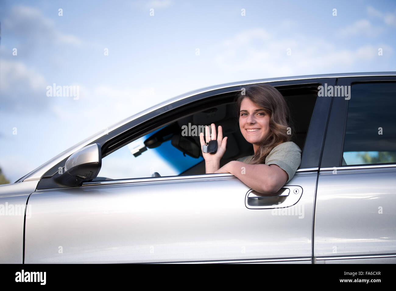 Teenage girl sitting in a car holding up  keys to new car Stock Photo