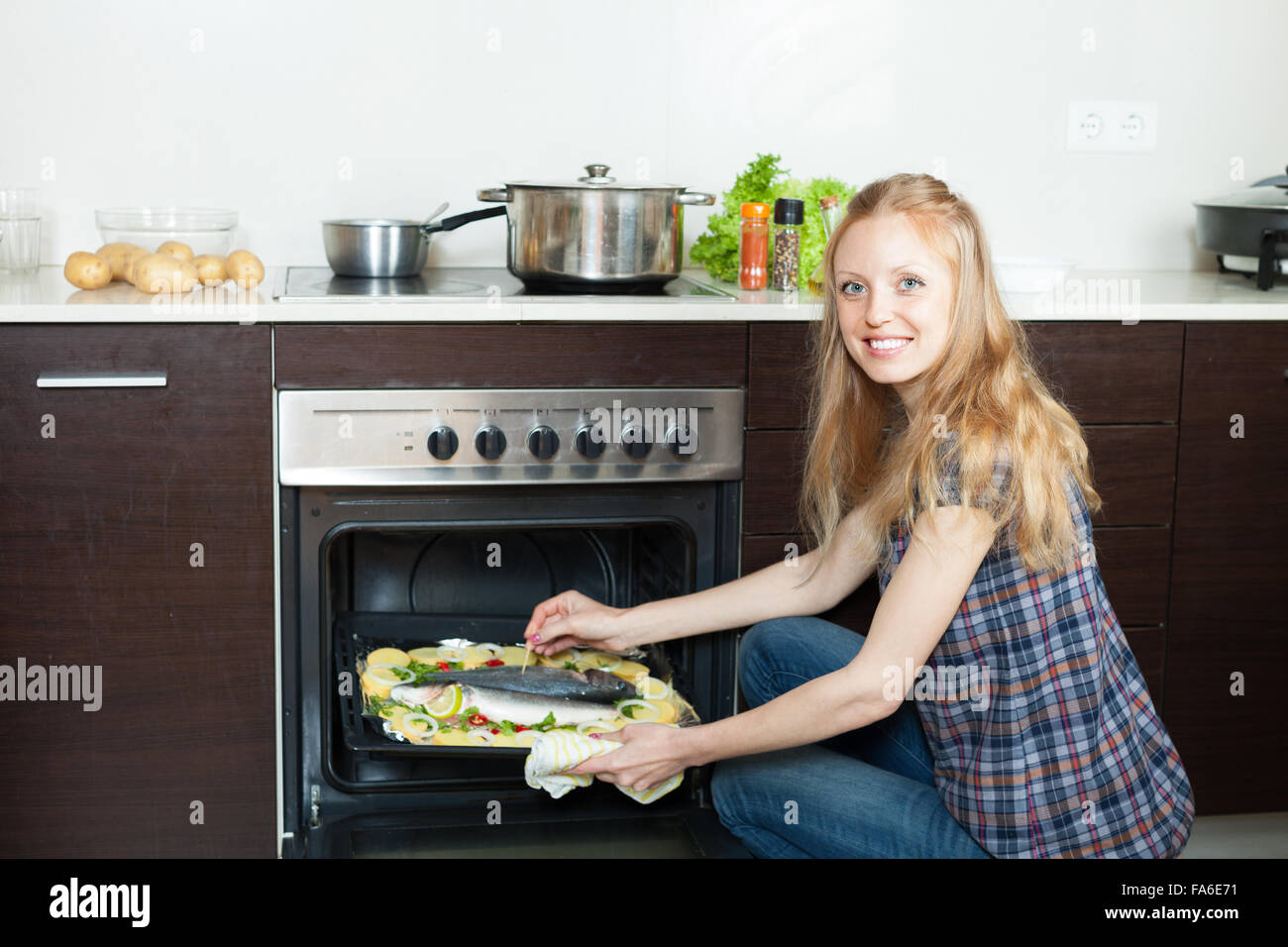 housewife cooking saltwater fish and potatoes on sheet pan in oven