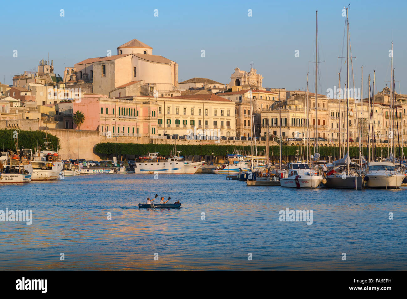Syracuse Sicily skyline, view of two canoeists with a dog onboard gliding through the harbour of Ortygia (Ortigia) Syracuse, Sicily. Stock Photo