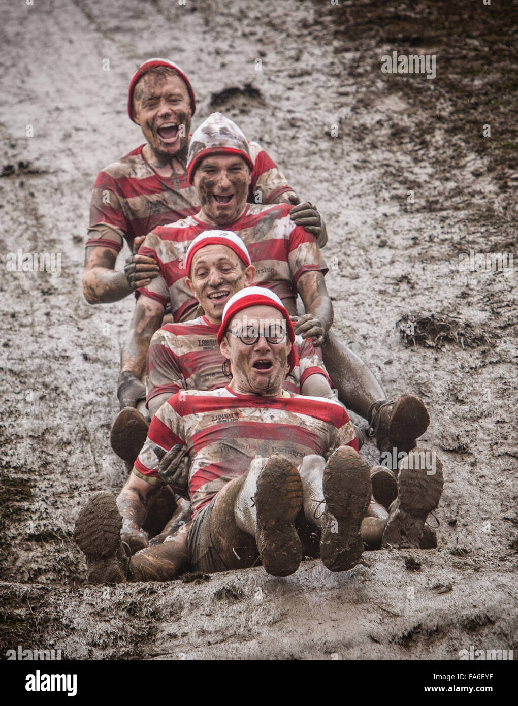 Mud Sliders. Friends enjoy a Tough Mudder event at Broughton Hall Estate, Yorkshire Stock Photo