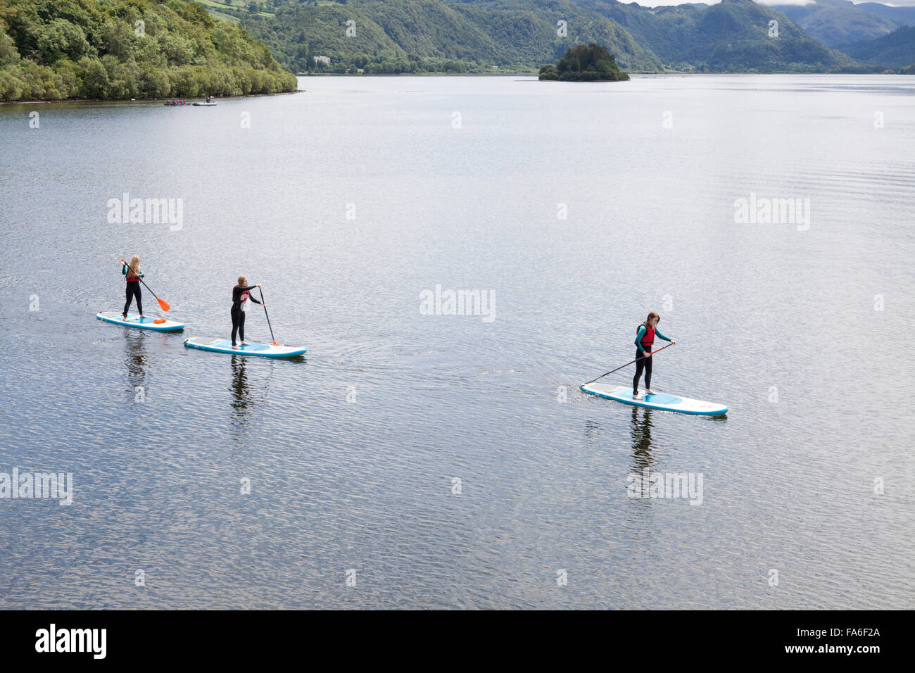 Three young women paddle boarding on Derwentwater in the Lake District