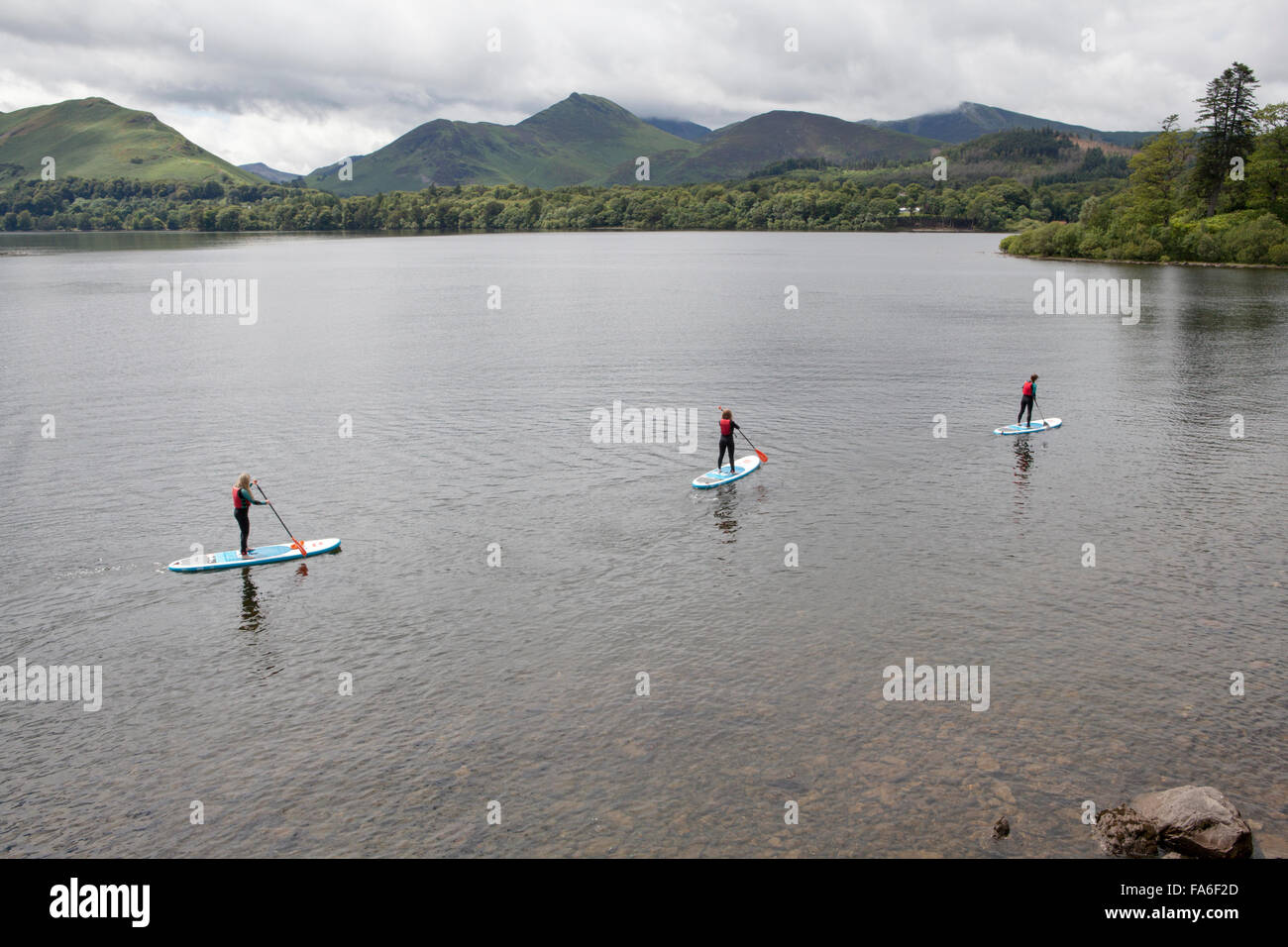 Three young women paddle boarding on Derwentwater in the Lake District