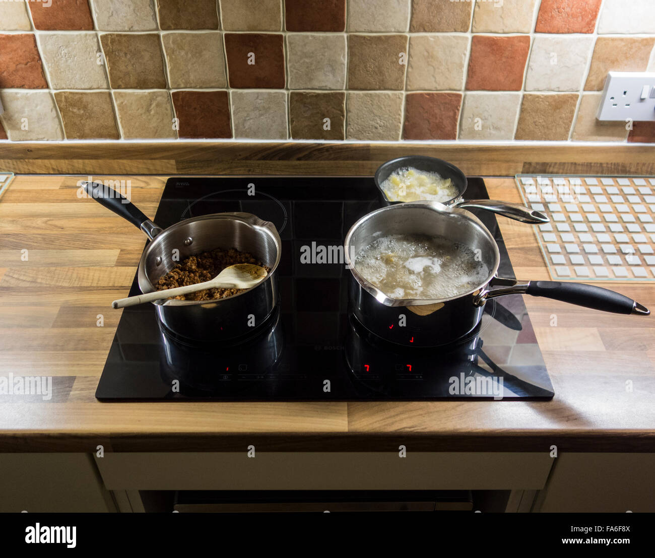 Pasta and sauce being cooked on an induction hob. Stock Photo
