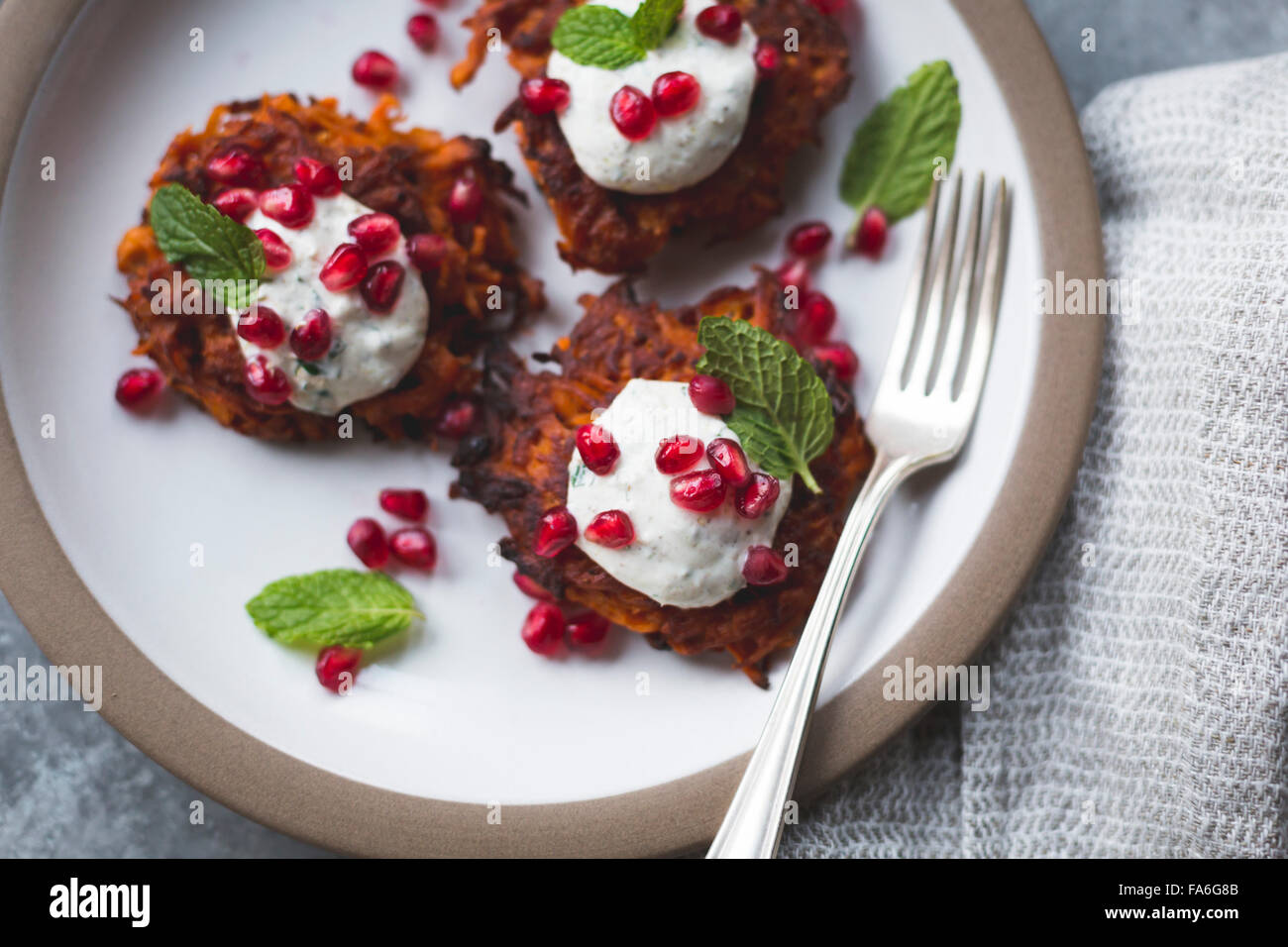 Harissa sweet potato latkes with spiced yogurt, mint and pomegranate, gluten-free. Stock Photo