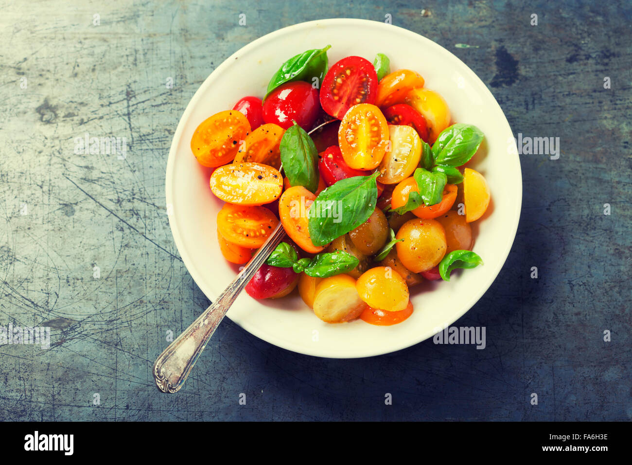 Fresh tomatoes with basil leaves in a bowl on vintage background Stock ...