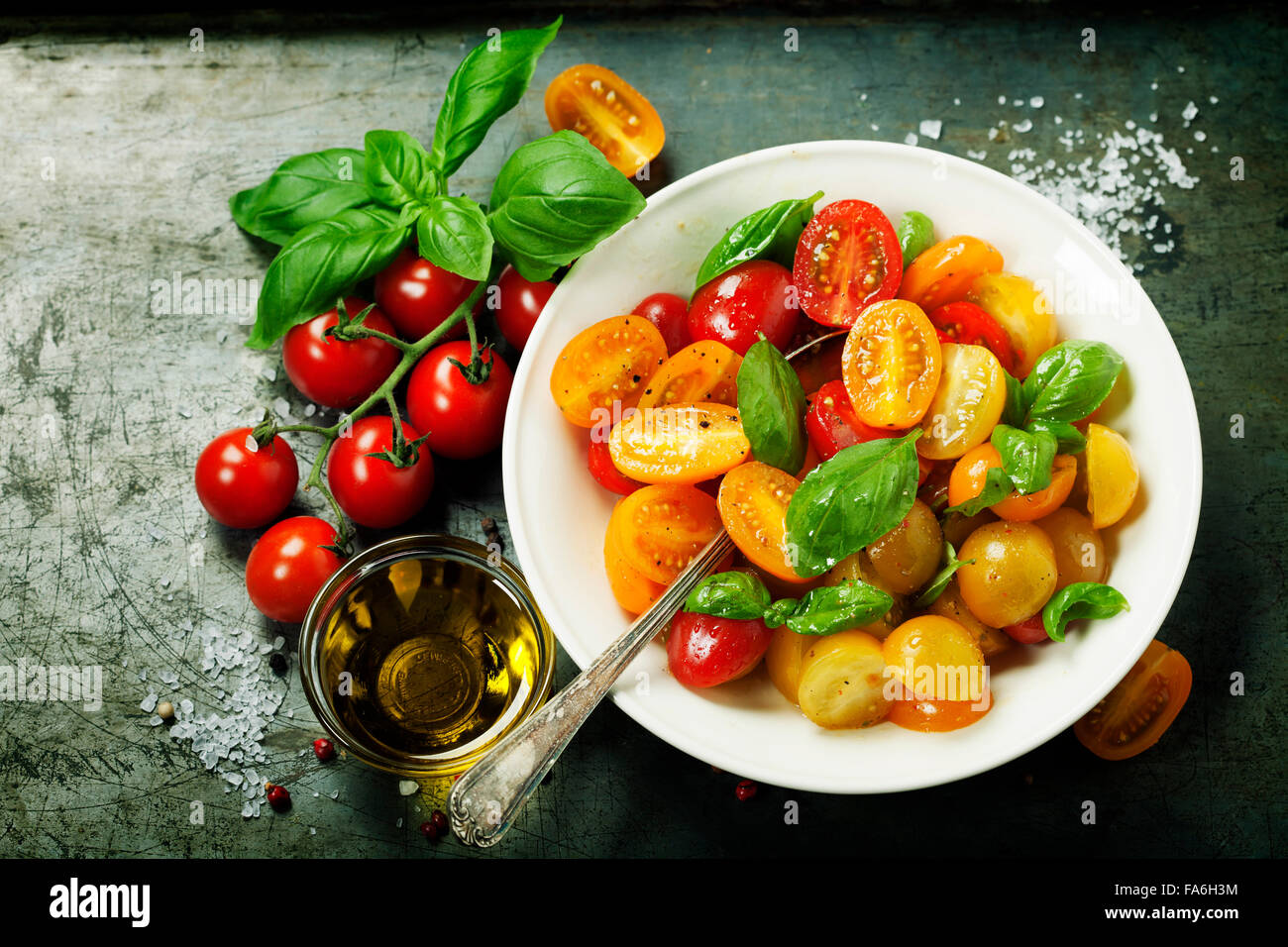 Fresh tomatoes with basil leaves in a bowl on vintage background Stock ...
