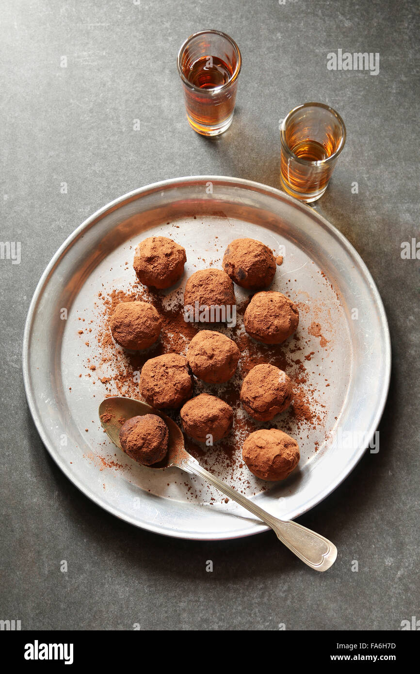 Chocolate truffles on an aluminum plate with 2 glasses of liqueur on background Stock Photo