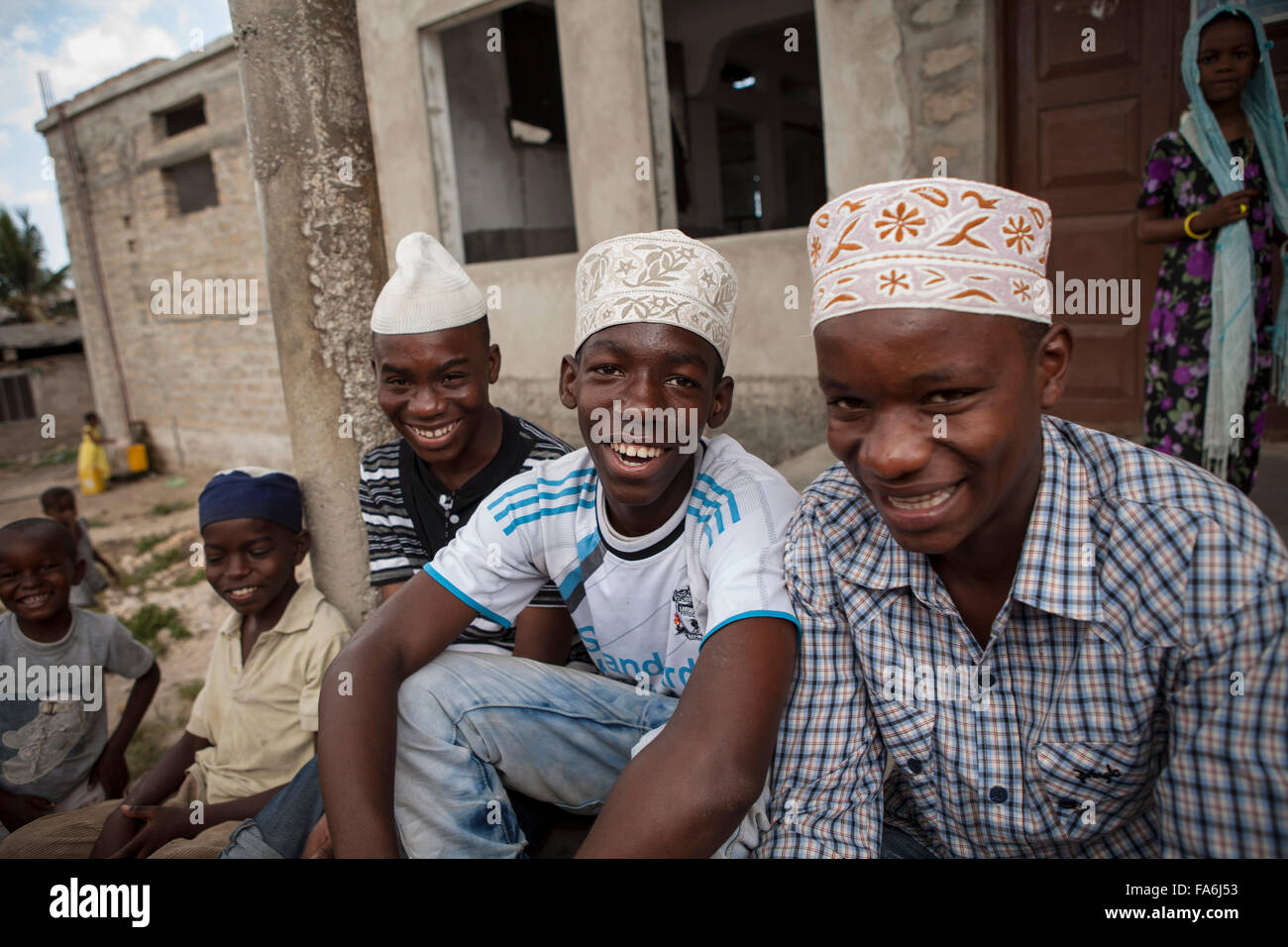 Young men sit on the steps of the Raudhwa Mosque in Zanzibar, Tanzania. Stock Photo