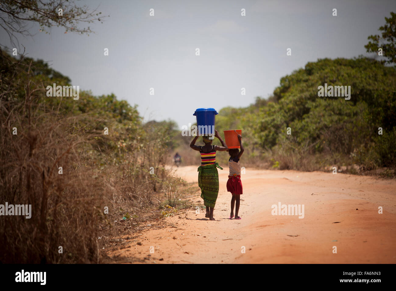 Girls return home from drawing water at an access point in Mecupes village, Mozambique. Stock Photo