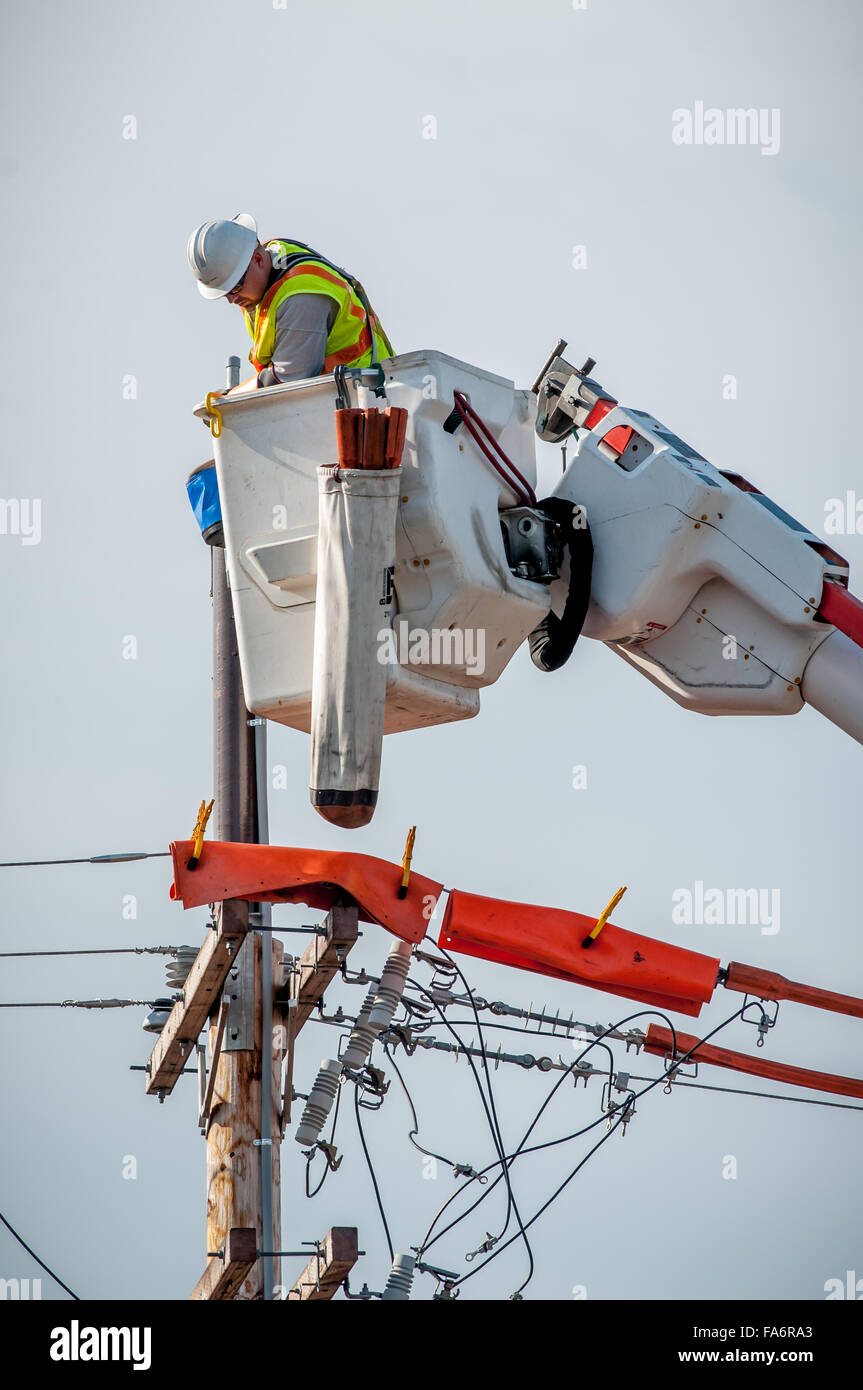 This hard working wireman is high on the job as he rewires this electric pole, It is not what one calls' Pole Dancing,' Stock Photo