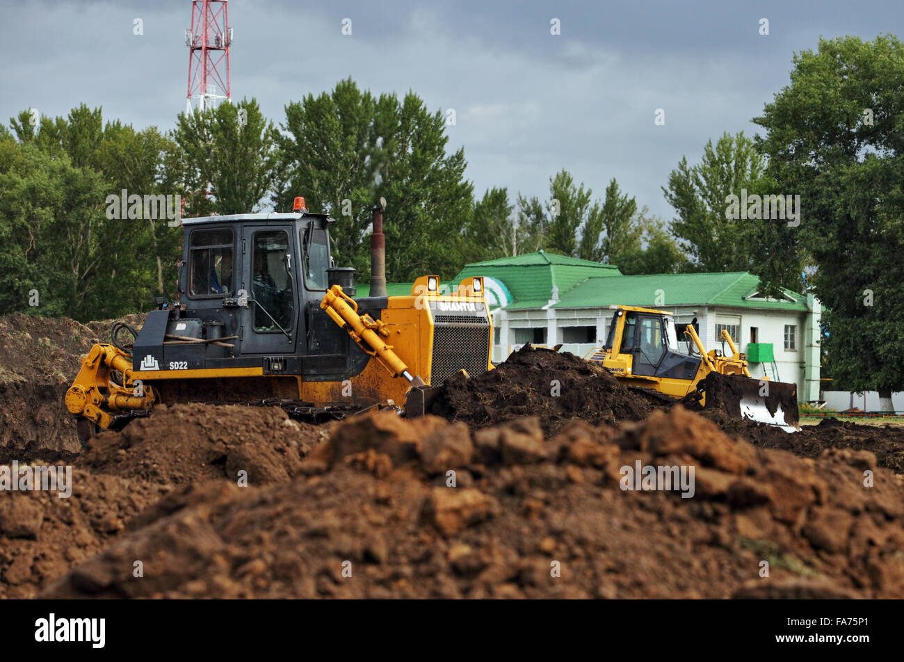 Two large yellow bulldozer moves earth at a construction site Stock Photo