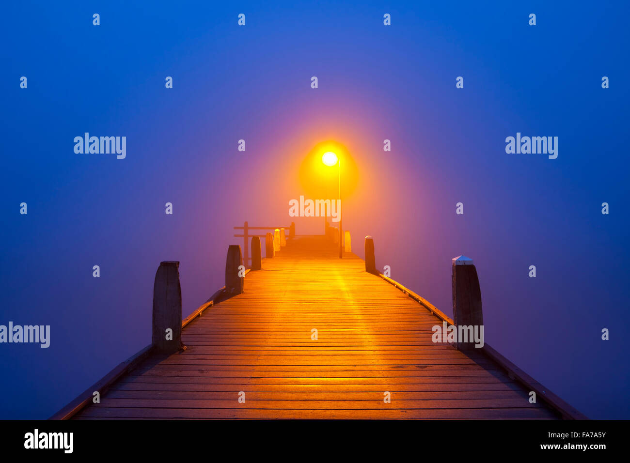 A jetty with a lamppost on a foggy morning at dawn. Stock Photo