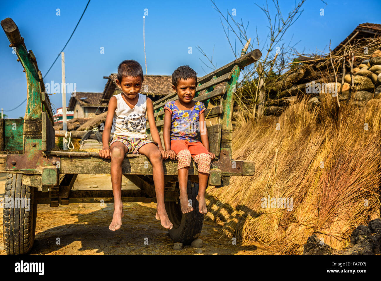 Two nepalese boys sitting on a wooden cart Stock Photo
