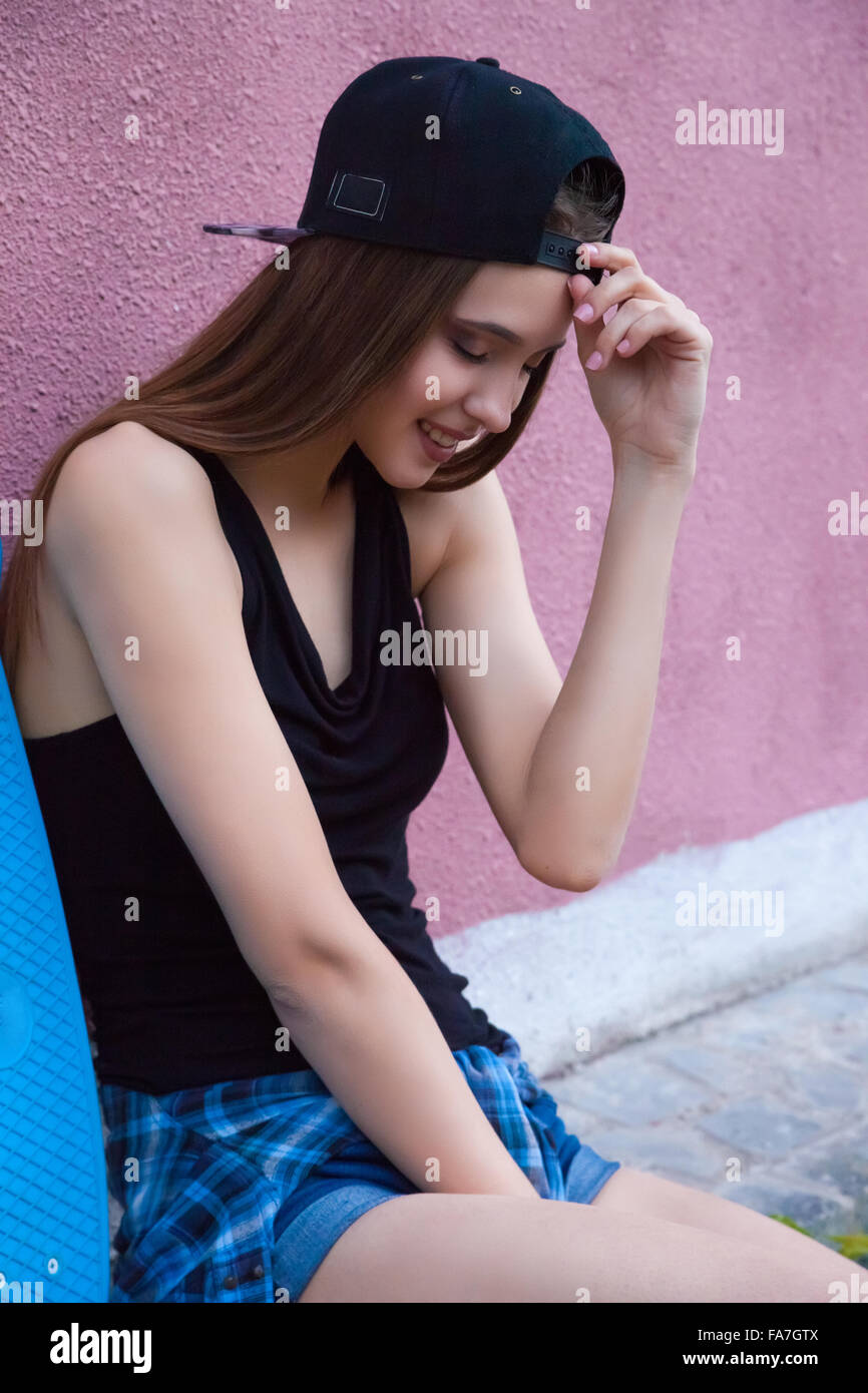 young girl wearing cap and shorts over pink wall Stock Photo