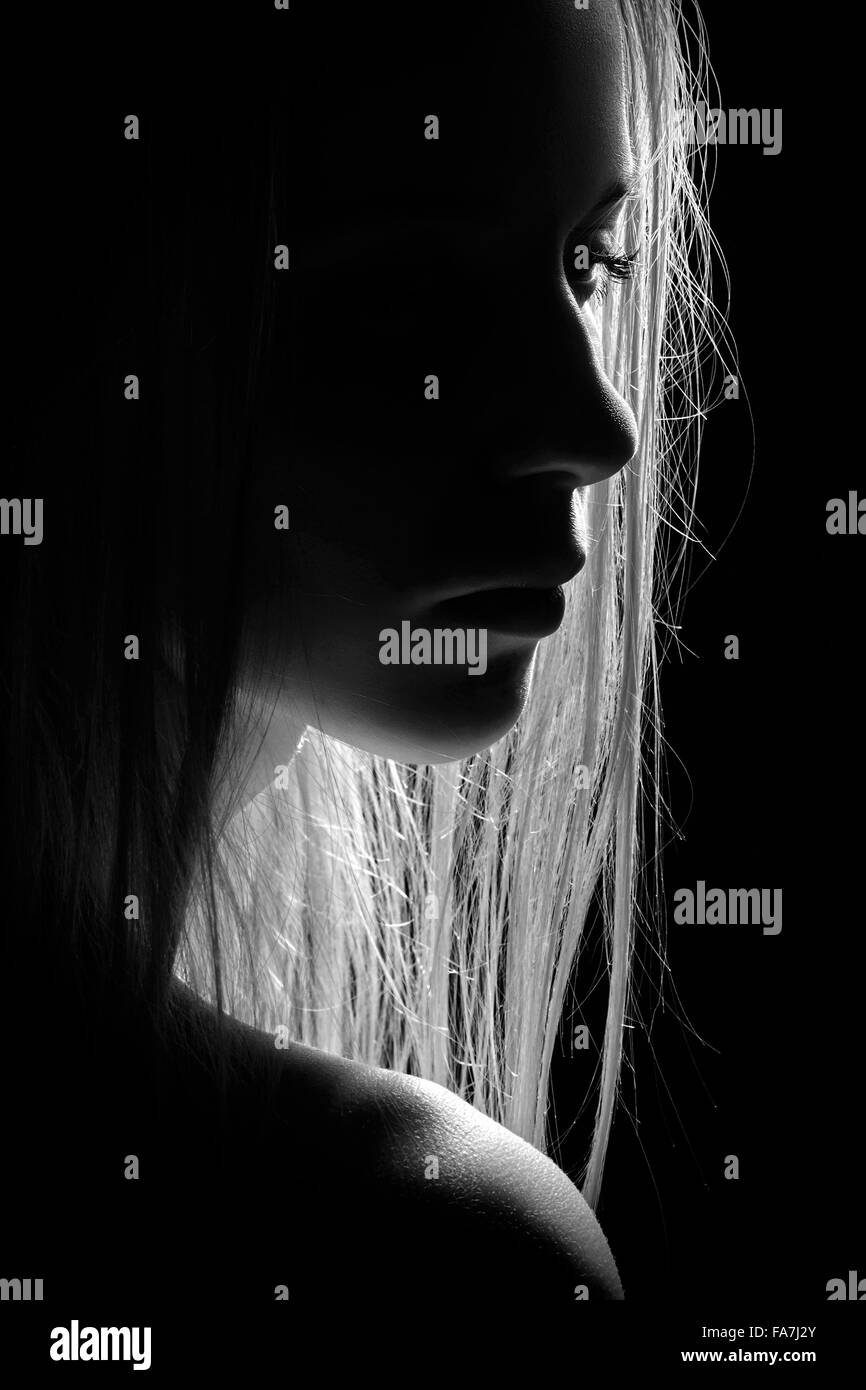 sad female profile silhouette in dark, monochrome image Stock Photo