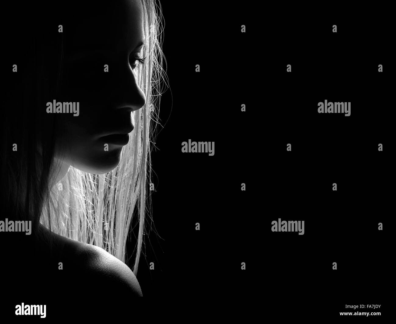 sad female profile silhouette in dark, monochrome image with copyspace Stock Photo