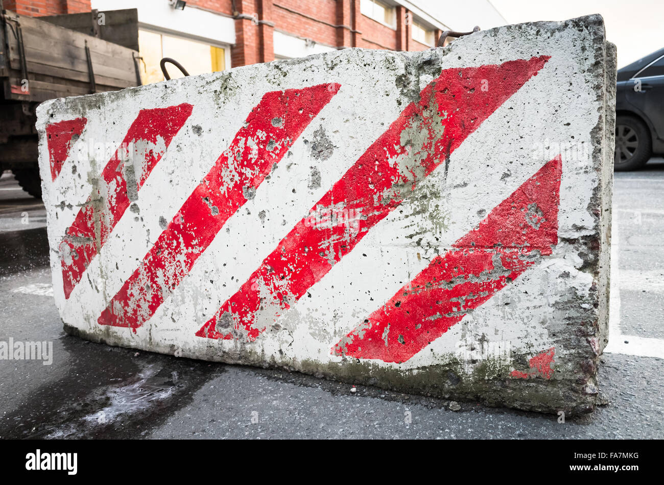 closeup photo of concrete road block with warning red and white diagonal striped pattern Stock Photo