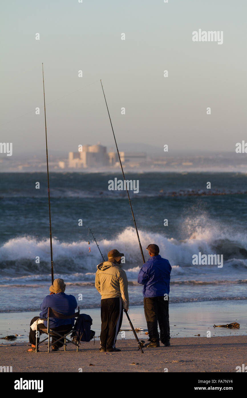 Fishermen against the backdrop of Koeberg nuclear power station, Melkbosstrand, Cape Town, South Africa Stock Photo
