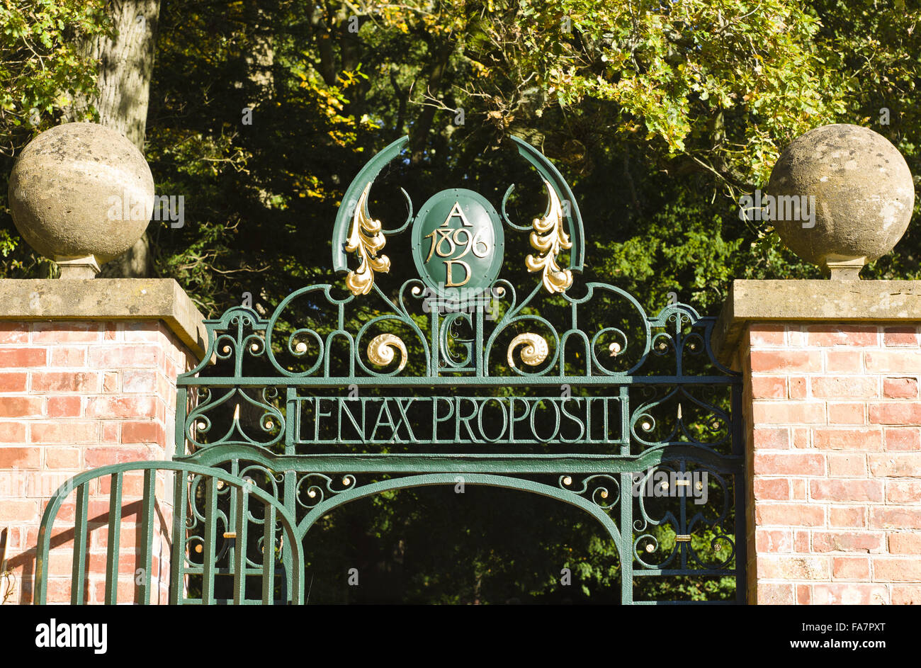 Wrought-iron gate to the Kitchen Garden at Tyntesfield, North Somerset. The shield is inscribed '1896 A.D. in top arch decoration. Below this is the Latin quotation 'TENAX PROPOSITI', meaning 'Firm of purpose'. Stock Photo