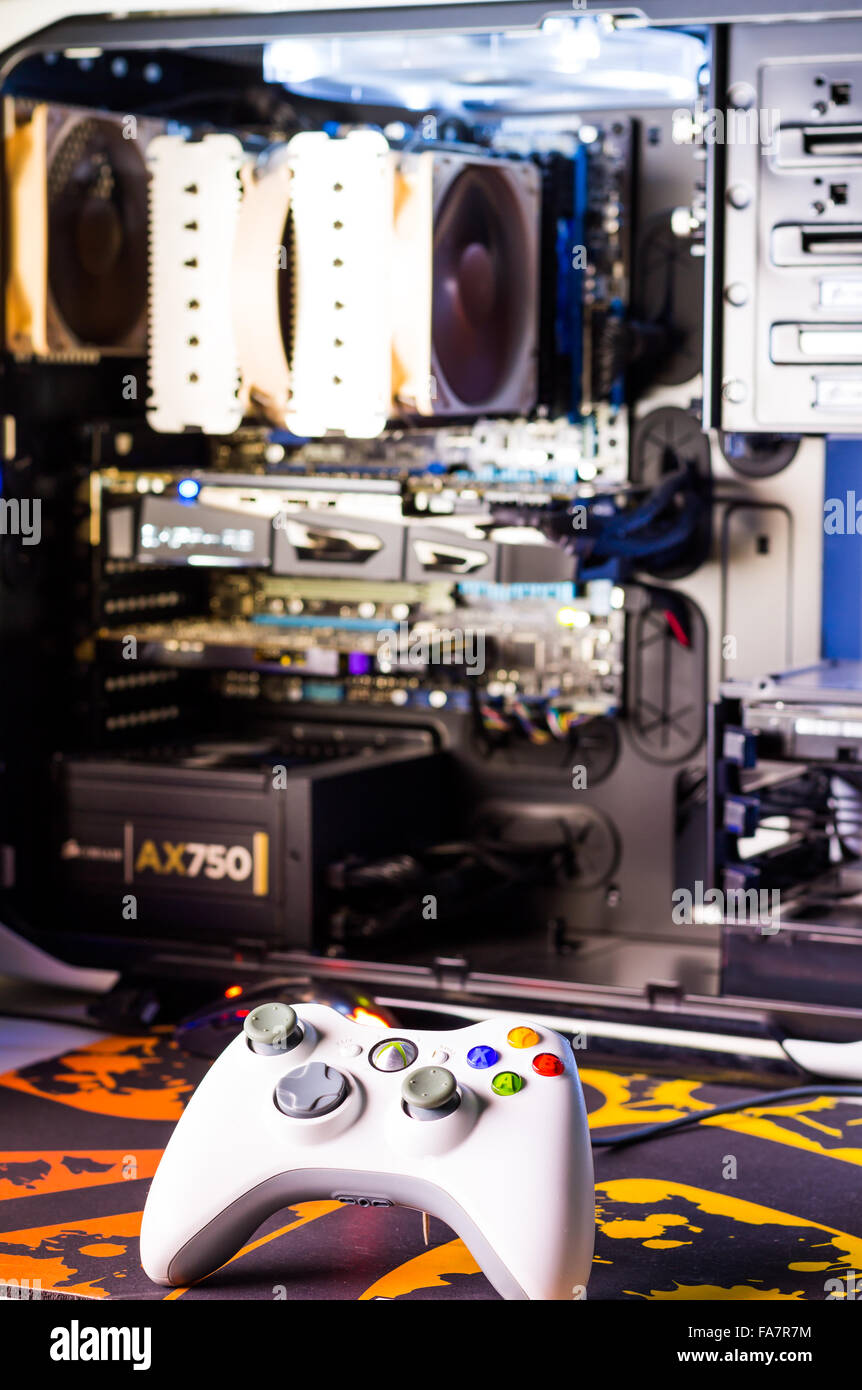 Custom built desktop computer for gaming on the table with joystick, monitor, keyboard, chair under low light. Selective focus. Stock Photo
