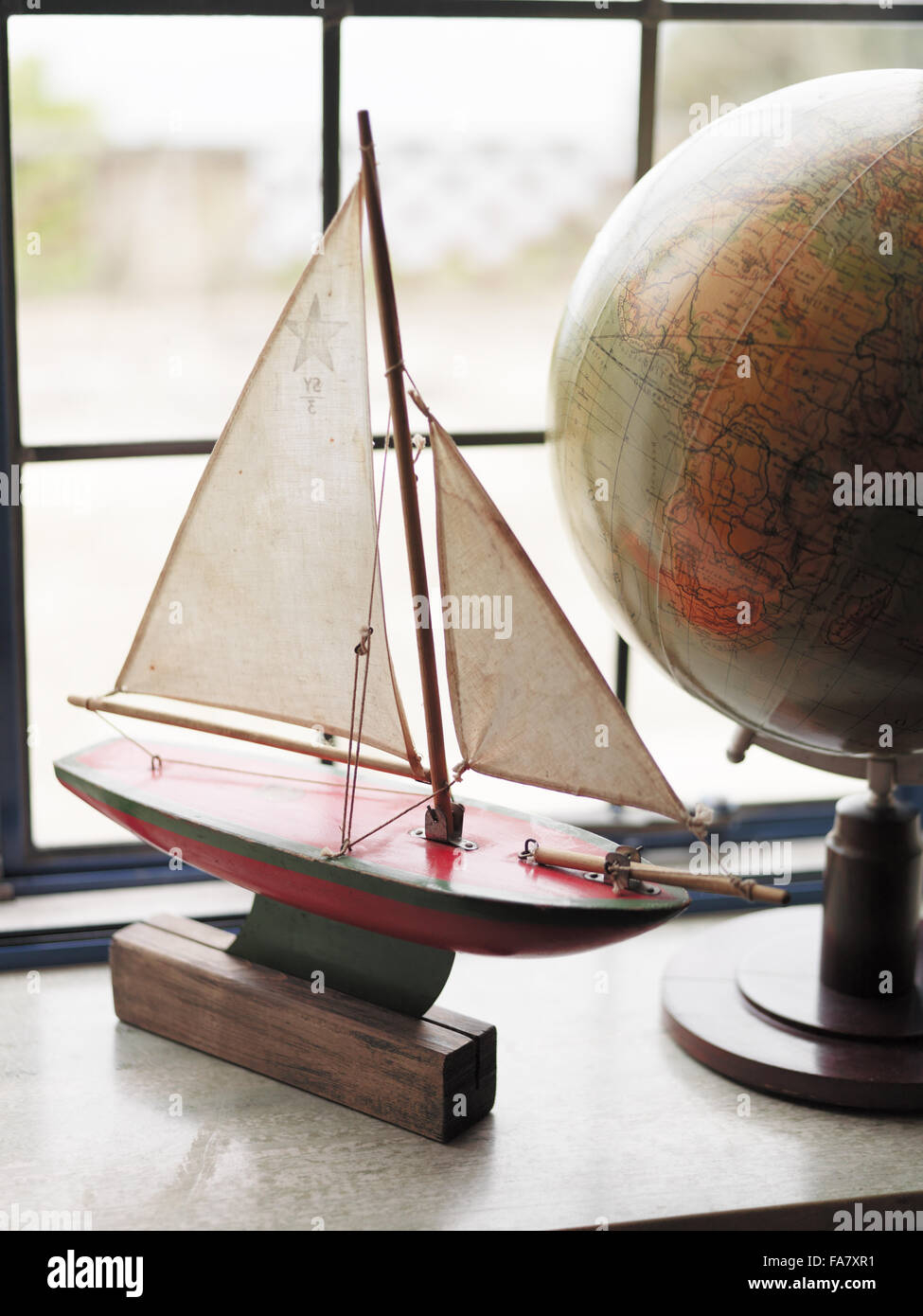 A vintage model boat and a globe, displayed on a windowsill in Portland House, Dorset. The house was built in 1935 for Geoffrey Bushby and is now available for hire as National Trust holiday accommodation. Stock Photo