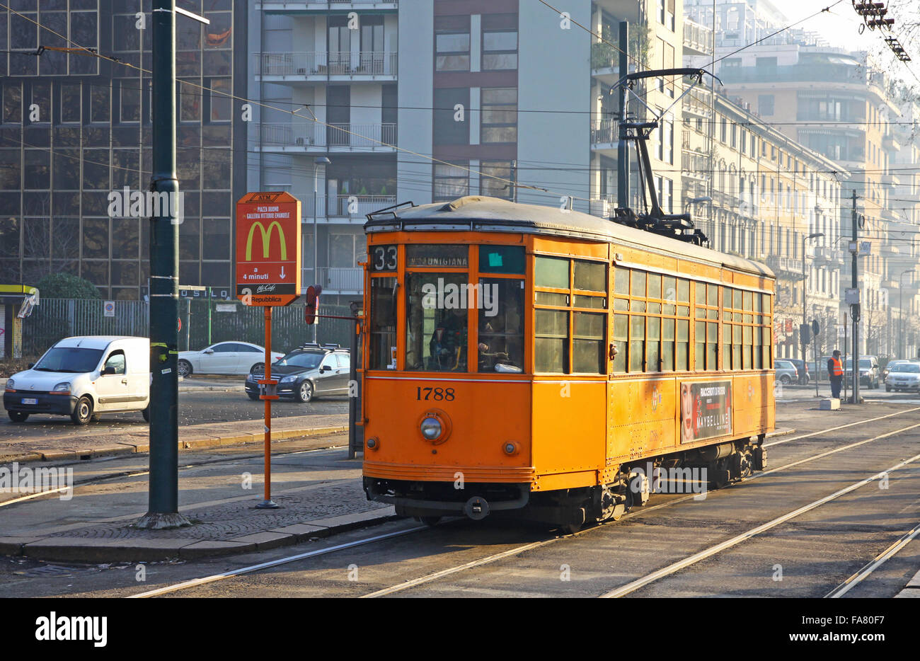 MILAN, ITALY - DECEMBER 31, 2010: Old traditional orange tram (Peter Witt streetcar) on the street of Milan. Milan tramway netwo Stock Photo
