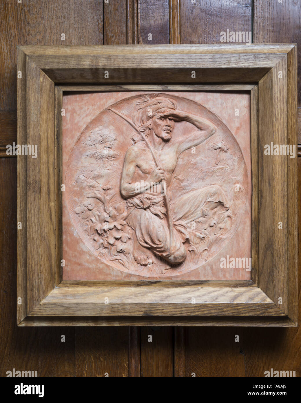 Plaque showing a kneeling man in the Exhibition Room at Bateman's, East Sussex. Oak, Terracotta. National Trust Inventory Number 761586. Bateman's was the home of the writer Rudyard Kipling from 1902 to 1936. Stock Photo