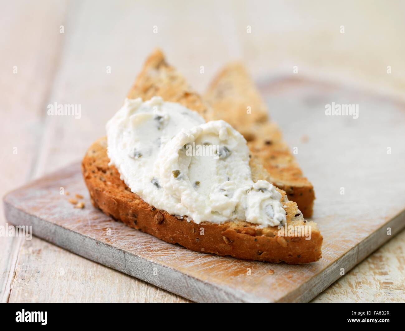 Onion and chive soft cheese smeared on toasted sliced wholegrain bread