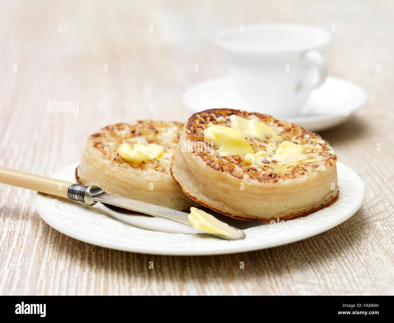 Melting butter on toasted crumpets with butter knife on plate Stock Photo