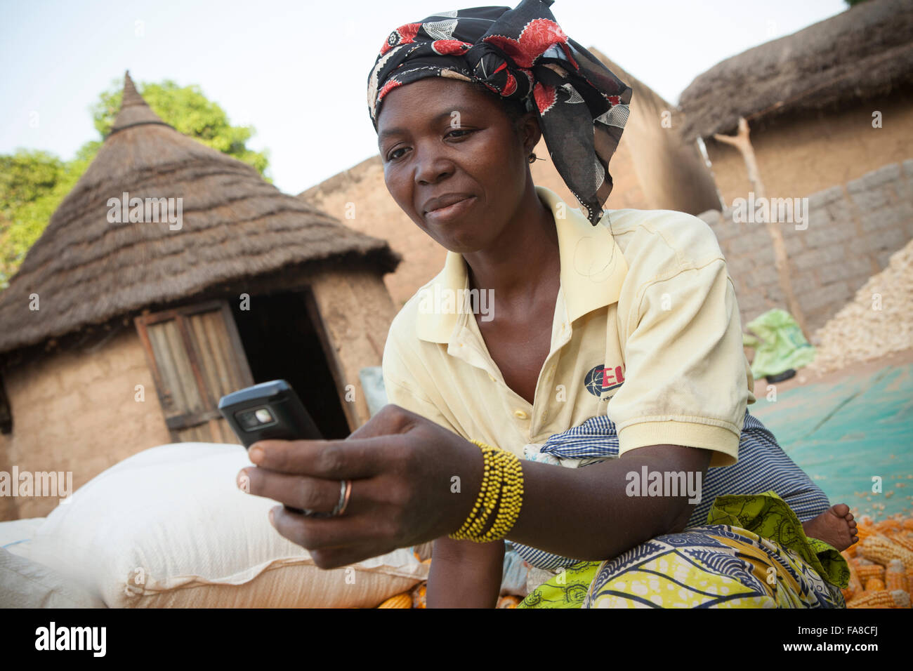 A farmer uses mobile phone technology to compare prices at various markets within Banfora Department, Burkina Faso, West Africa. Stock Photo