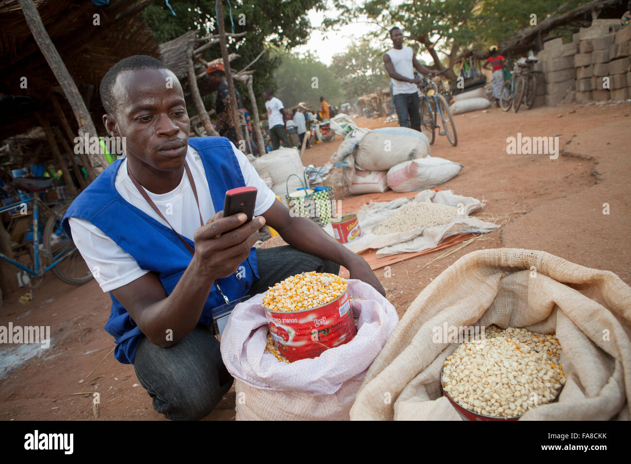 A commodities buyer uses mobile phone technology to compare prices at various markets in Burkina Faso, W. Africa. Stock Photo