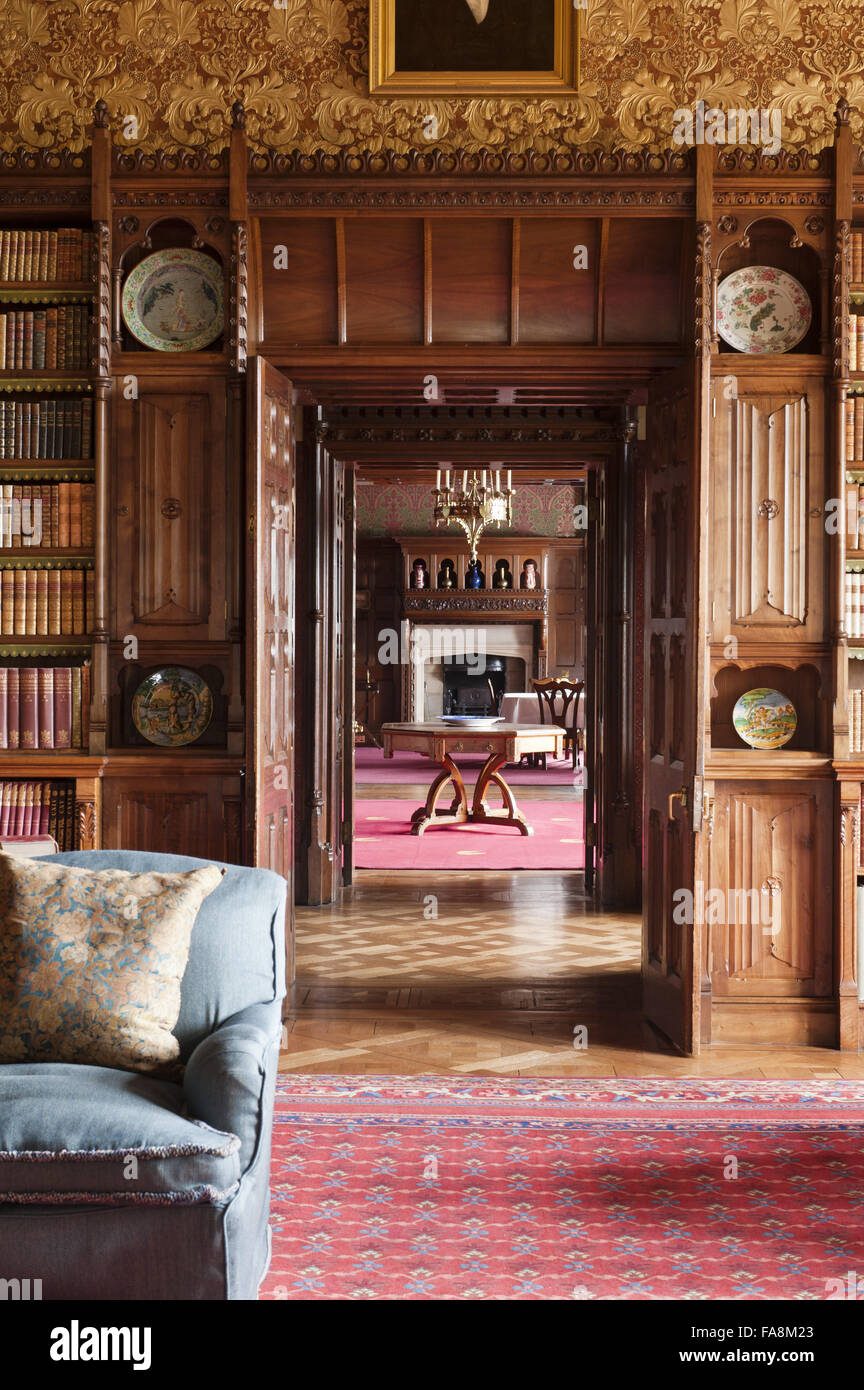 View from the Library through the door to the Morning Room at Knightshayes Court, Devon. The bookcases are in a Gothic style with linenfold panelling by John Crace. Stock Photo