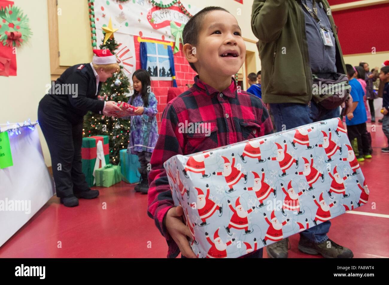 A young Native Alaskan boy smiles after receiving presents from volunteers during Operation Santa Claus December 5, 2015 in St. Mary's, Alaska. The program has been held for 59 years and brings Christmas cheer to underserved, remote villages across Alaska. Stock Photo
