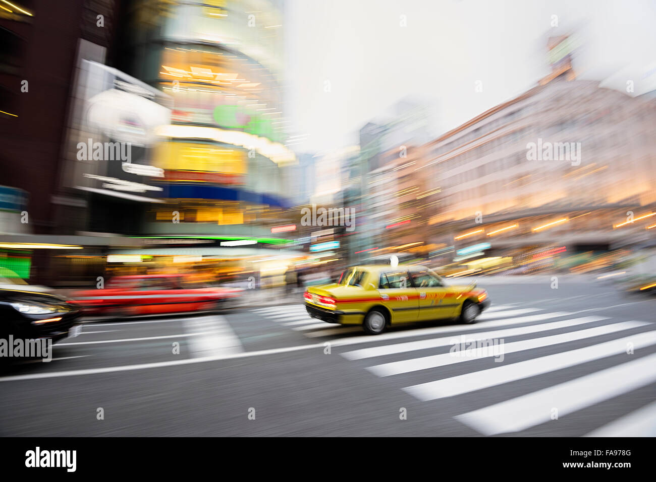 Tokyo, Japan - Dec 10, 2015: Motion blurred taxi at the heart of Ginza District in Tokyo. Wako Building is at the background. Stock Photo