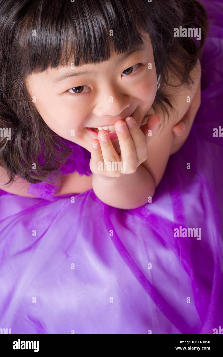A portrait of a cute, happy and young Japanese girl in a purple dress. Stock Photo