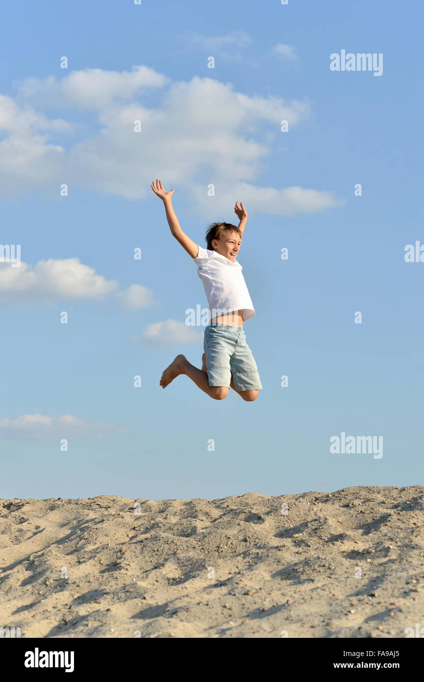 Cheerful boy jumping on sand Stock Photo Alamy