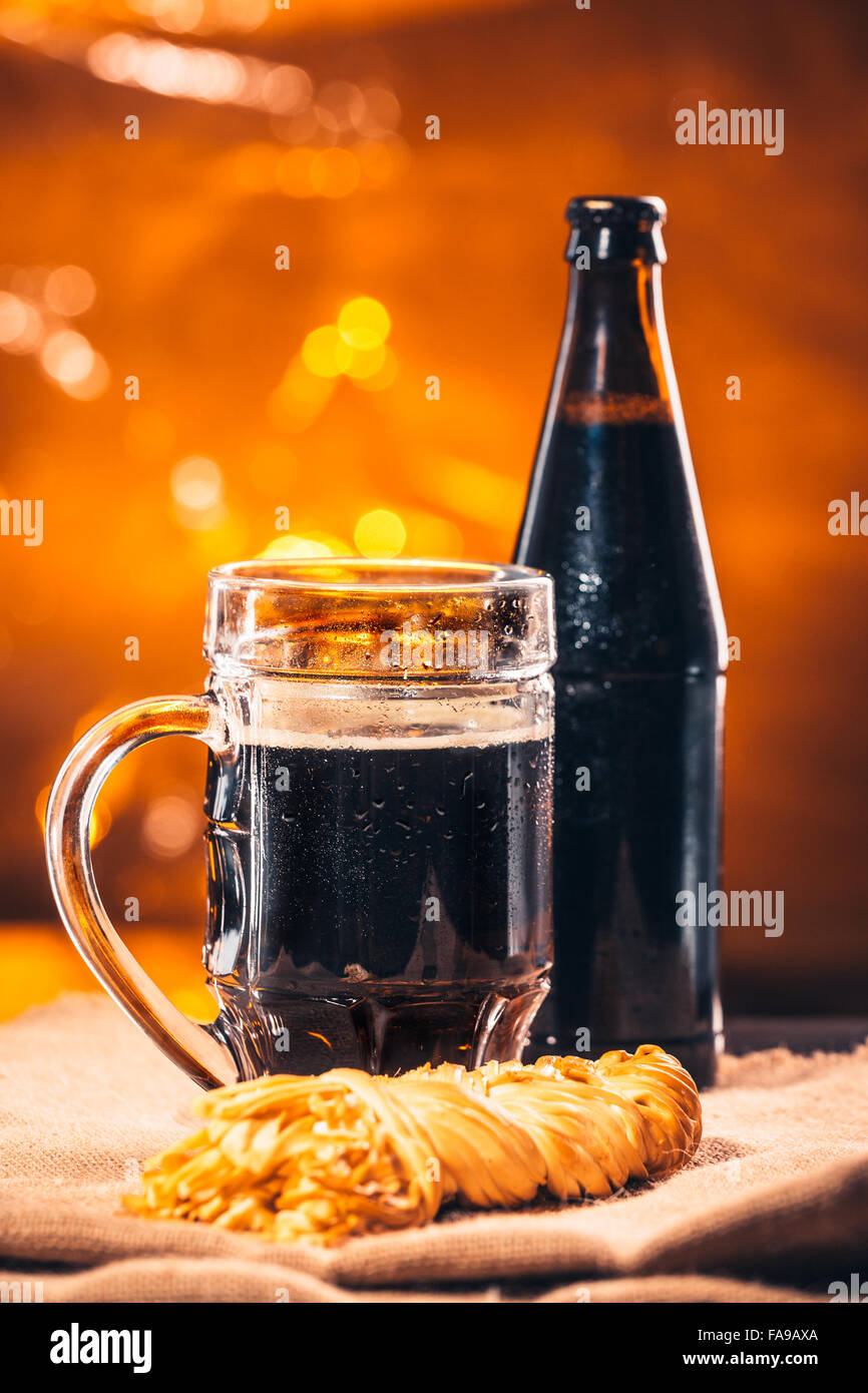 bottle and glass of fresh dark beer with smoked cheese braid on sacking Stock Photo