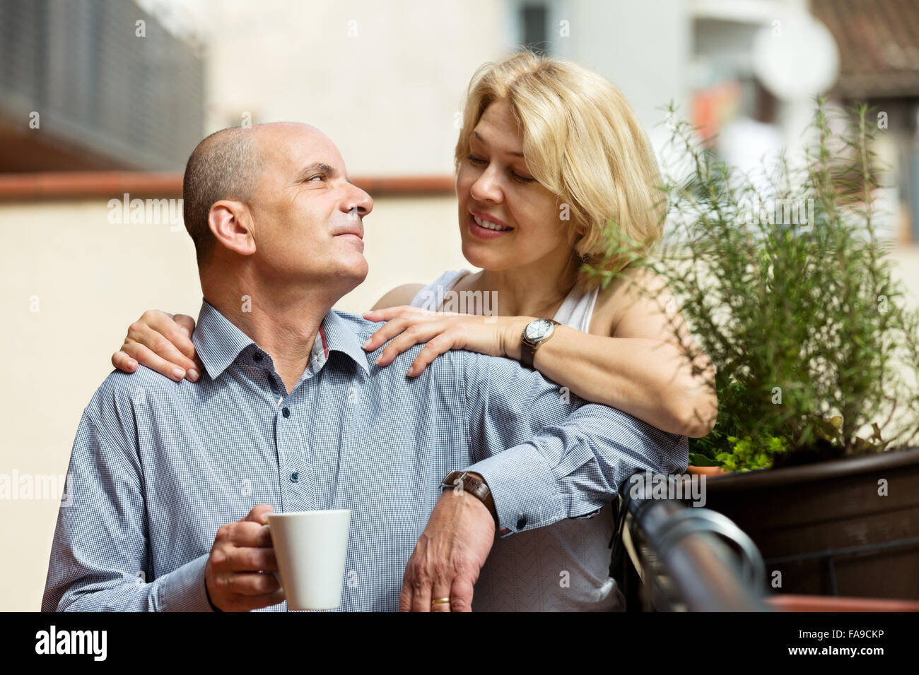 Positive elderly couple having morning coffee at balcony Stock Photo