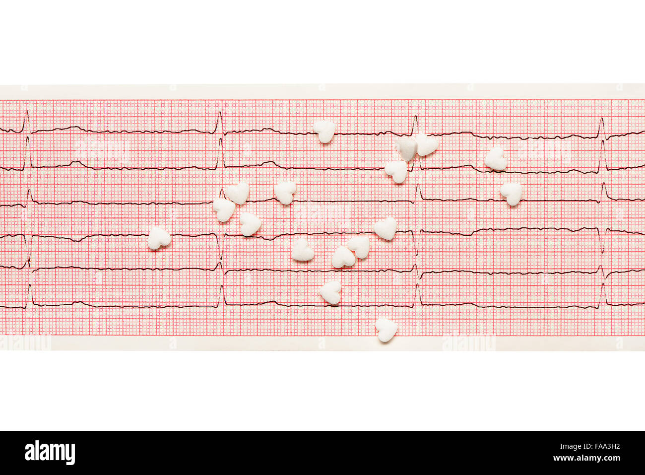 White heart shape tablets on paper ECG results isolated on white background. Clipping path included. Stock Photo
