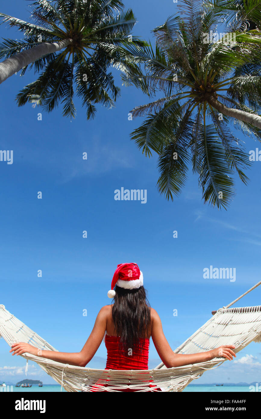 Christmas vacation - woman in santa hat on the beach in hummock Stock Photo