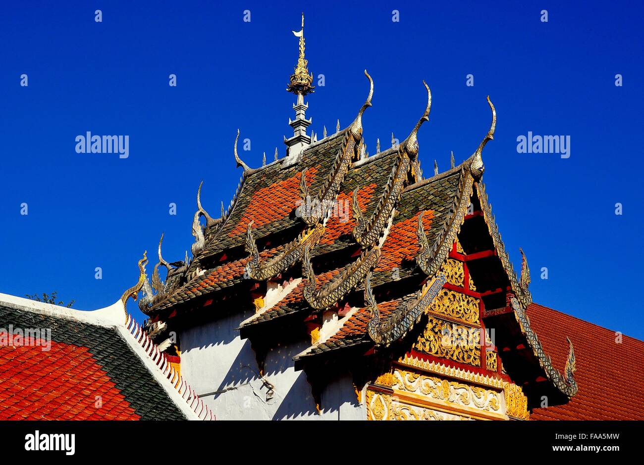 Lamphun, Thailand - December 28, 2012: Opulent gabled roof with ornate gilded chofah ornaments at Thai wat * Stock Photo