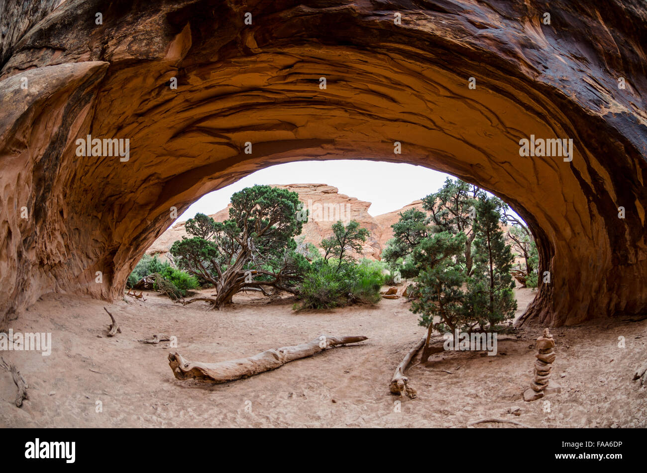 A cairn and juniper trees through Navajo Arch Stock Photo
