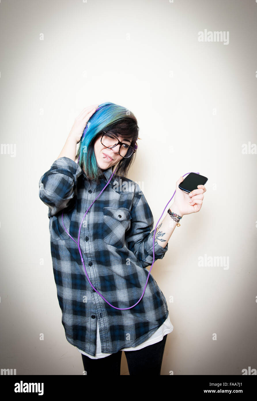 Young teen woman with mobile phone and head phones enjoying listening music Stock Photo